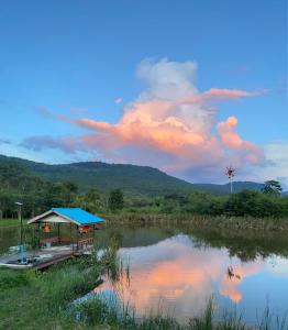 un bâtiment avec un toit bleu à côté d'un lac dans l'établissement Homtel Farmstay Campgrounds, à Pak Chong