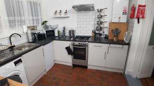 cocina con armarios blancos, fogones y fregadero en Puffin Place,Lloyd House en Haverfordwest