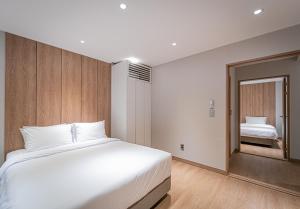 ein Schlafzimmer mit einem großen weißen Bett und ein Zimmer mit einem Doppelbett in der Unterkunft The Private Hamdeok in Jeju-do