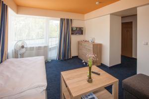 a room with a bed and a table with a vase at Tauras Center Hotel in Palanga