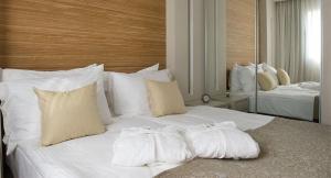 a white bed with two pillows on it at מול החוף במלון רמדה נתניה in Netanya
