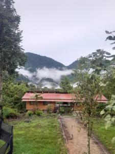 una casa en un campo con montañas en el fondo en Sendero de las aves, en Mindo