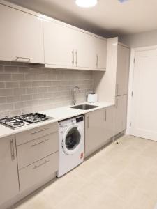 a kitchen with white cabinets and a washer and dryer at Entire Cozy Guest house in Galway