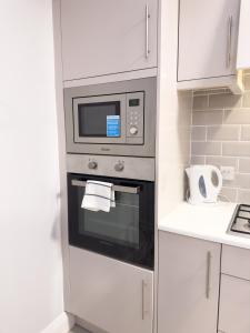 a microwave oven in a kitchen with white cabinets at Entire Cozy Guest house in Galway