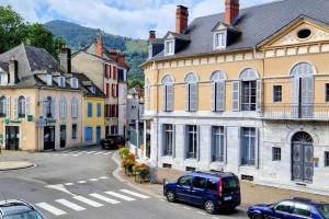 een stadsstraat met auto's geparkeerd voor gebouwen bij La Parqueterie - 2 pas des thermes - 6 voyageurs in Bagnères-de-Bigorre