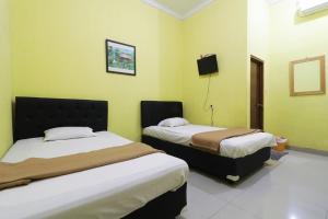 two beds in a room with green walls at Hotel Surabaya Jaya Bandara Soetta in Rawalembang