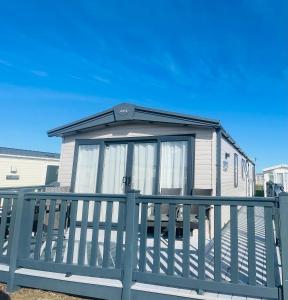 a small house with a blue fence at Pure-Living West Sands Sunshine and Sea View - 3 Bedroom lodge at SEAL BAY in Selsey