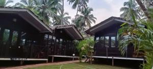 a house with black roofs and palm trees at Seascape by Sand Sapphire in Canacona