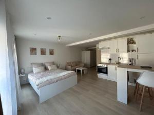 a white bedroom with a bed and a kitchen at Studio cocooning à Mirecourt in Mirecourt