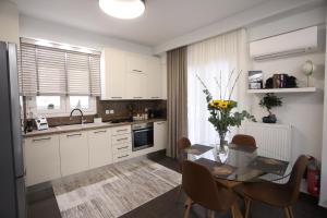a kitchen with white cabinets and a table with chairs at LA Larissa Luxury Apartments Thetis in Larisa