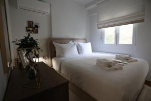 a bedroom with a bed with white sheets and a window at LA Larissa Luxury Apartments Thetis in Larisa
