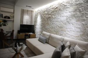 a living room with a white couch and a stone wall at LA Larissa Luxury Apartments Thetis in Larisa