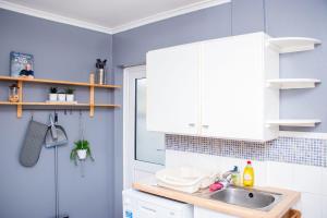 a kitchen with white cabinets and a sink at Cosy Windsor Cottage - Free Parking included in Windsor