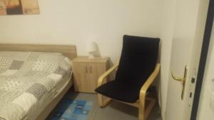 a bedroom with a black chair next to a bed at Da lillo in Fuldatal