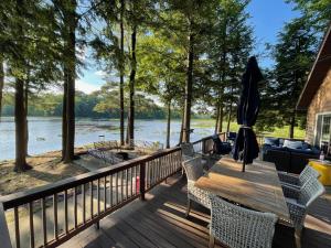 a deck with chairs and a wooden table with an umbrella at Mom & Pop's: Waterfront,Nature,Togetherness in Cambridge Springs