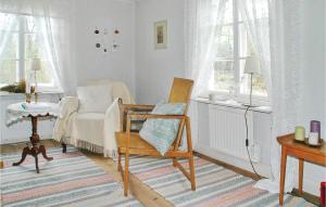 Lovely Home In Hrryda With Kitchen في Hindås: غرفة معيشة مع كرسي وأريكة ونوافذ