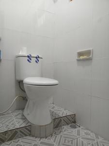 ein weißes WC im Bad mit Fliesenboden in der Unterkunft umah kampung bendul in Penebel