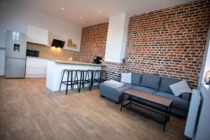 a living room with a couch and a brick wall at Appartement Duplex en Centre-Ville de Cambrai - 110m2 in Cambrai