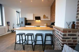 eine Küche mit drei Barhockern und einer Theke in der Unterkunft Appartement Duplex en Centre-Ville de Cambrai - 110m2 in Cambrai