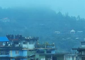 un grupo de edificios en una ciudad nebulosa en Hotel Moomsie Itanagar Arunachal Pradesh, en Itānagar