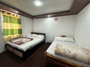 a room with two beds and a window at Sushi guest - mini in Nuwara Eliya