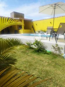 un patio con ombrellone e sedie e una piscina di Morada de Angatu a Itanhaém
