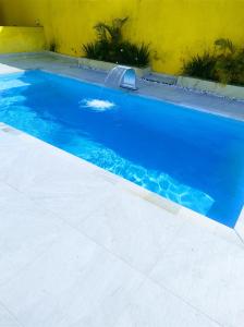 una grande piscina blu accanto a un muro giallo di Morada de Angatu a Itanhaém