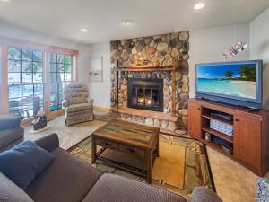 ein Wohnzimmer mit Kamin und Fernseher in der Unterkunft Anchors Away Cottage on Big Spirit Lake in Orleans