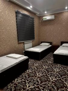 three beds in a room with a window on the wall at Karakalpak Travel in Nukus