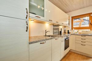 a kitchen with white cabinets and a sink at Alpen-Chalet Benzeck in Reit im Winkl +9 photos