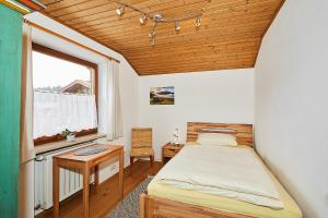 a bedroom with a bed and a table and a window at Alpen-Chalet Benzeck in Reit im Winkl