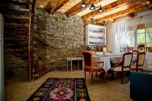 a dining room with a table and chairs and a stone wall at La Tarani in Vatra Dornei