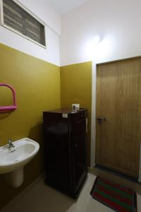 La salle de bains est pourvue d'un lavabo et d'une porte en bois. dans l'établissement Wayanad regal residency, à Kalpatta