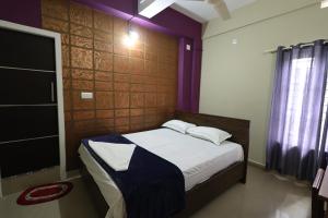 - une chambre avec un lit dans une pièce aux murs violets dans l'établissement Wayanad regal residency, à Kalpatta