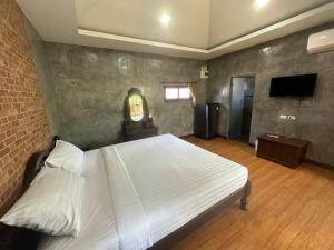 a bedroom with a white bed and a television at The Beatles Lagoon in Ban Na Bon