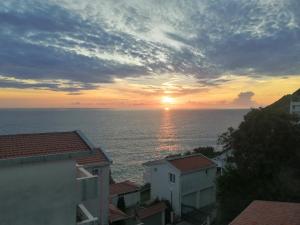 a sunset over the ocean with houses and buildings at Apartmani Seaside in Dobra Voda +9 photos