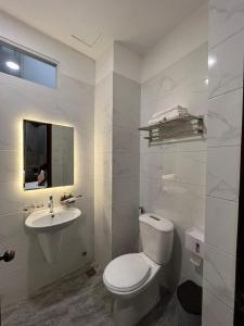 a white bathroom with a toilet and a sink at Happy Hotel in Ho Chi Minh City