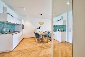 a kitchen and dining room with white cabinets and a wooden floor at Hermitage Vital Hotel in Maria Wörth