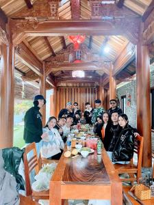 un grupo de personas sentadas alrededor de una mesa de madera en The Hillside Homes, en Phong Nha