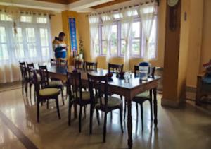 uma sala de jantar com uma mesa longa e cadeiras em HOTEL MON KYIMOJONG ARUNACHAL PRADESH em Tawang