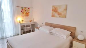 B&B Le Albarelle في ألبا: غرفة نوم بيضاء مع سرير ومكتب