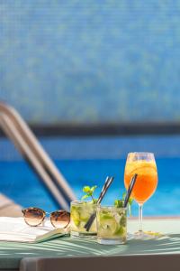a drink and sunglasses on a table next to a pool at Hotel Madeira in Funchal