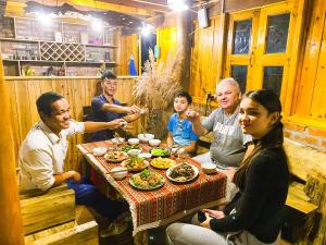 eine Gruppe von Menschen sitzt um einen Tisch herum und isst in der Unterkunft Pham's House - Homestay & Cafe in Sa Pa + 108 Fotos