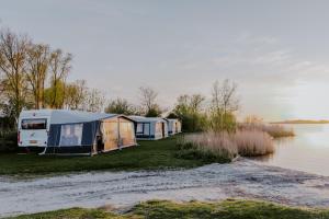 een rij tenten geparkeerd naast een waterlichaam bij Holiday Caravan Holle Poarte Makkum in Makkum