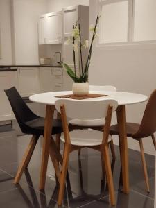 a white table with chairs and a vase with flowers on it at Luxury Loft Apartment in Kuwait