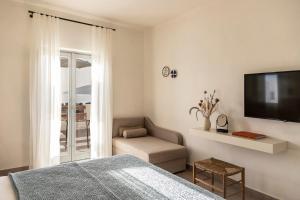 um quarto com uma cama, uma televisão e uma cadeira em Nysis Koufonisia em Koufonisia