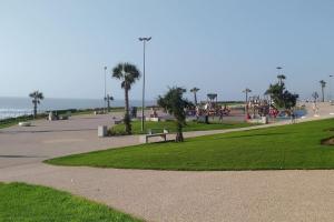 un parque con un banco y un parque infantil con palmeras en Appartement vue mer Anza Agadir, en Agadir