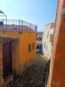 une allée entre deux bâtiments avec un bâtiment jaune dans l'établissement Casa Anna, à Borgio Verezzi