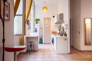 a kitchen with white appliances and a red stool at Artistique et pragmatique in Marseille