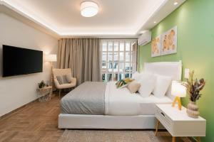 um quarto com uma cama branca e uma televisão de ecrã plano em Phaedrus Living: The Emerald Studio em Atenas